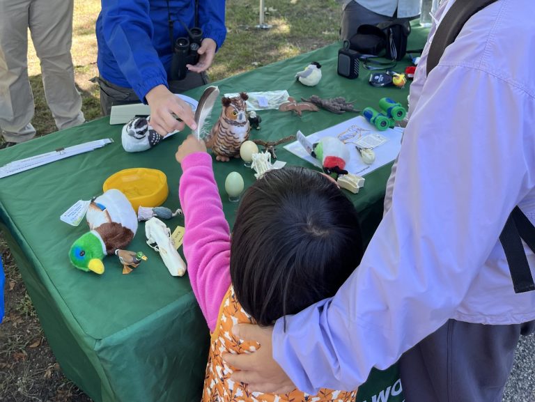 Intern handing a duck feather to a small child